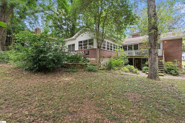 view of yard featuring a deck, stairway, and a sunroom