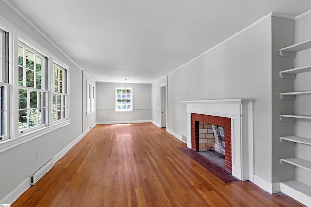 unfurnished living room with wood finished floors, visible vents, a brick fireplace, an inviting chandelier, and crown molding