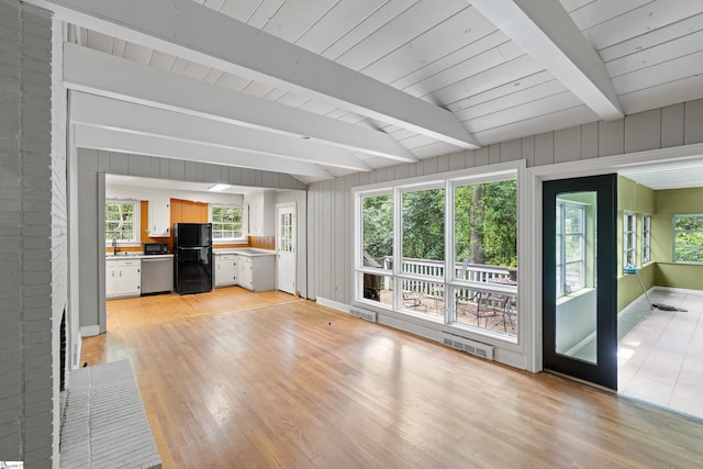 unfurnished living room featuring beam ceiling, visible vents, and light wood-style floors