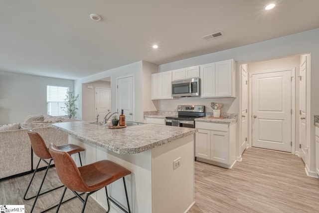 kitchen with sink, a center island with sink, white cabinets, and appliances with stainless steel finishes