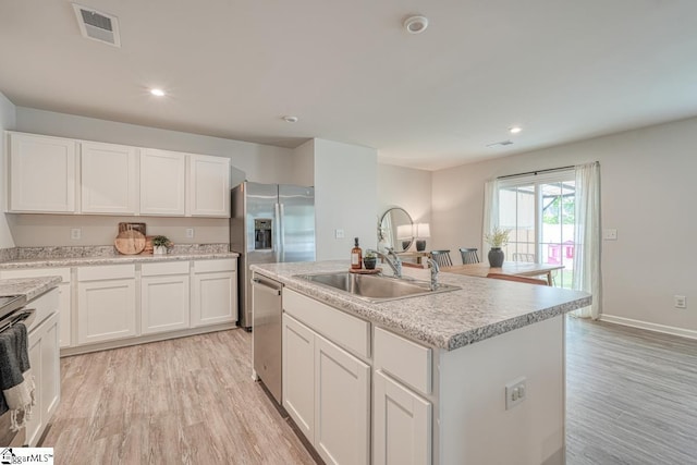 kitchen with sink, light hardwood / wood-style flooring, appliances with stainless steel finishes, an island with sink, and white cabinets