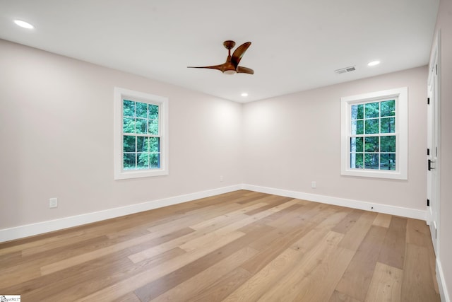 empty room featuring ceiling fan, a wealth of natural light, and light hardwood / wood-style floors