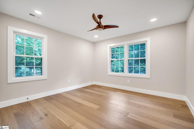 empty room with a healthy amount of sunlight, light hardwood / wood-style flooring, and ceiling fan