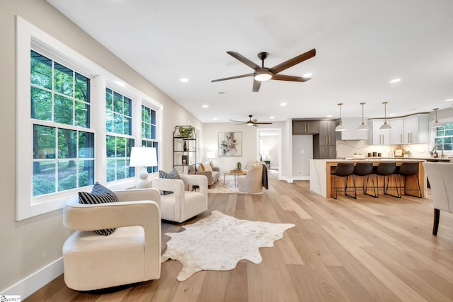 living room featuring ceiling fan, light wood-type flooring, and plenty of natural light