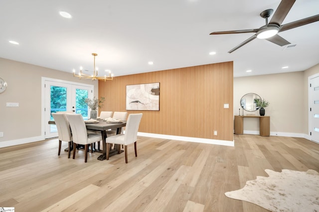 dining space with ceiling fan with notable chandelier, french doors, and light wood-type flooring