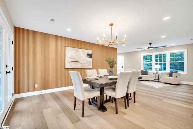 dining room featuring ceiling fan with notable chandelier and light wood-type flooring