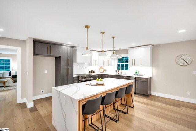 kitchen with stainless steel appliances, decorative backsplash, pendant lighting, light wood-type flooring, and a kitchen island