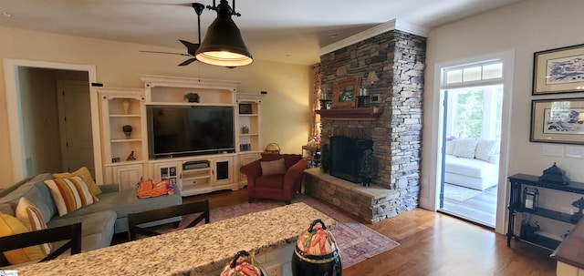 living room featuring wood-type flooring, a fireplace, and ceiling fan