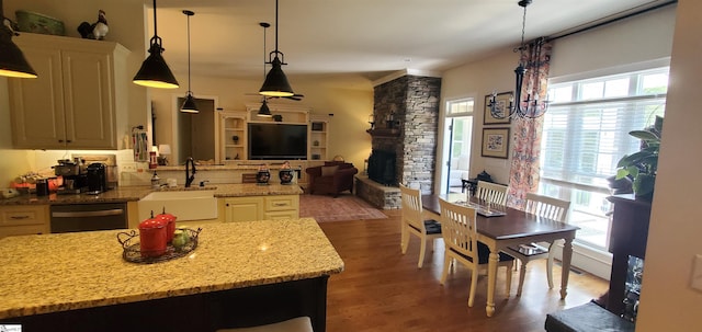 kitchen with dishwasher, backsplash, light stone counters, wood-type flooring, and sink