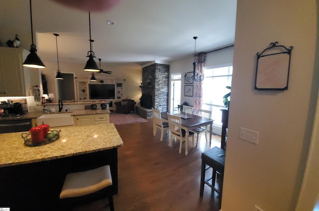 kitchen with dark hardwood / wood-style floors, light stone counters, a breakfast bar area, and sink