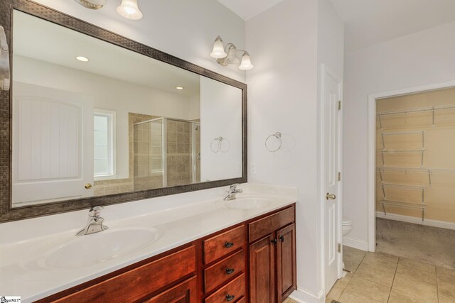 bathroom with toilet, double sink vanity, walk in shower, and tile patterned flooring