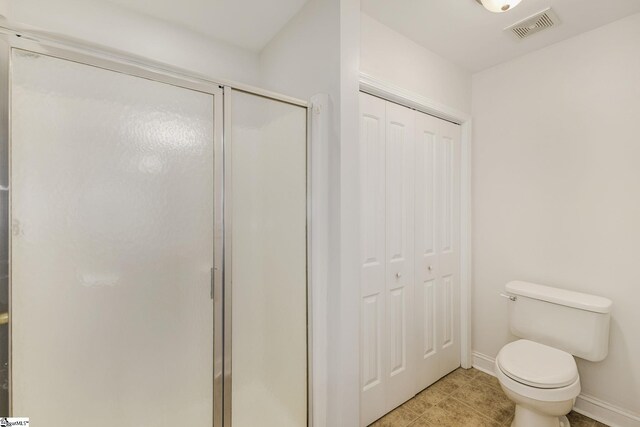 bathroom with tile patterned flooring, toilet, and an enclosed shower