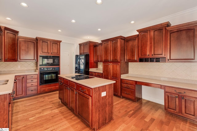 kitchen with tasteful backsplash, black appliances, a kitchen island, light wood-type flooring, and built in desk