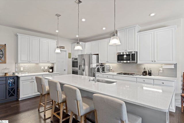 kitchen featuring white cabinets, backsplash, dark wood-type flooring, appliances with stainless steel finishes, and sink