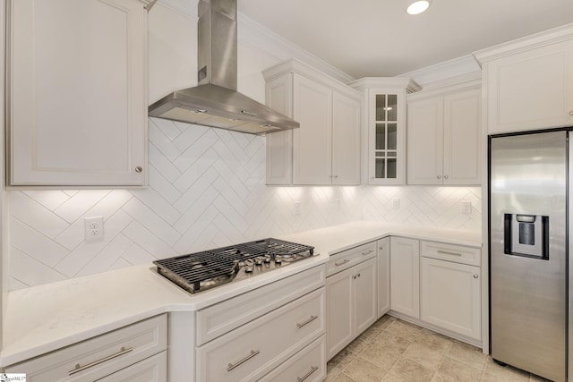 kitchen with backsplash, stainless steel appliances, wall chimney exhaust hood, and light tile patterned floors