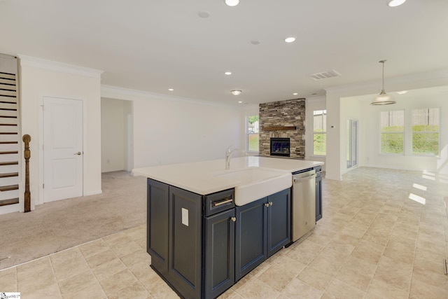 kitchen with dishwasher, a kitchen island with sink, a stone fireplace, light carpet, and sink