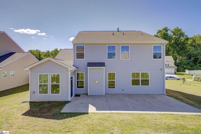 rear view of property featuring a garage, a patio area, and a lawn