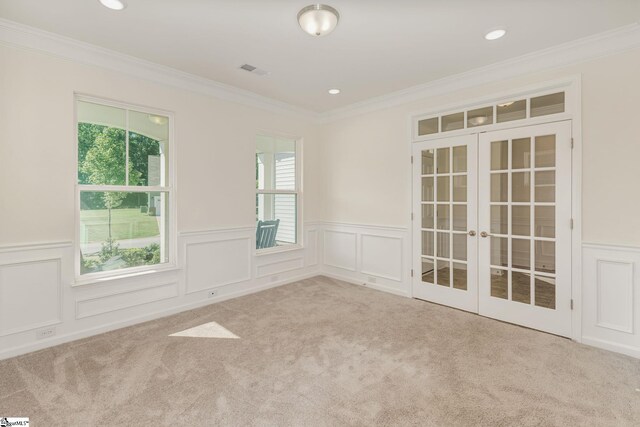 empty room with light carpet, french doors, a wealth of natural light, and ornamental molding