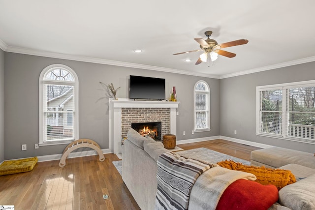 living room featuring crown molding, a brick fireplace, and hardwood / wood-style floors