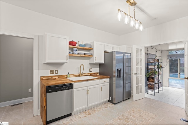 kitchen with butcher block counters, hanging light fixtures, white cabinets, and appliances with stainless steel finishes