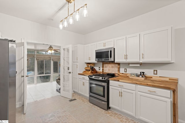 kitchen featuring french doors, wooden counters, decorative light fixtures, appliances with stainless steel finishes, and white cabinets