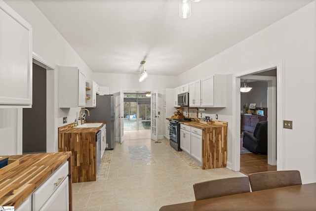 kitchen with gas range oven, wooden counters, and white cabinets