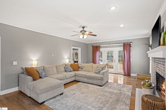 living room featuring crown molding, ceiling fan, a brick fireplace, and hardwood / wood-style flooring