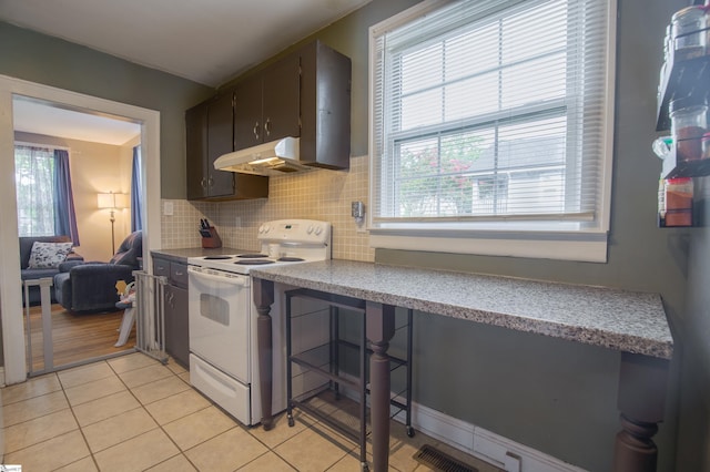 kitchen with decorative backsplash, light tile patterned flooring, a healthy amount of sunlight, and white range with electric cooktop