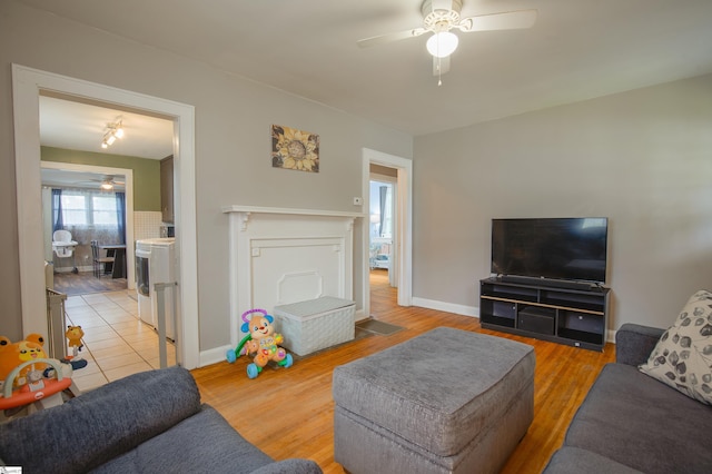 living room with wood-type flooring, separate washer and dryer, and ceiling fan