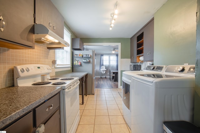 kitchen featuring washing machine and clothes dryer, white electric range, light tile patterned floors, stainless steel refrigerator, and ceiling fan