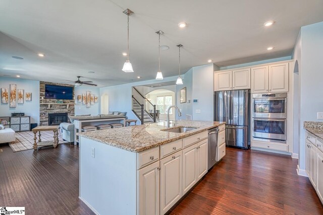 kitchen featuring a fireplace, dark hardwood / wood-style flooring, an island with sink, sink, and appliances with stainless steel finishes