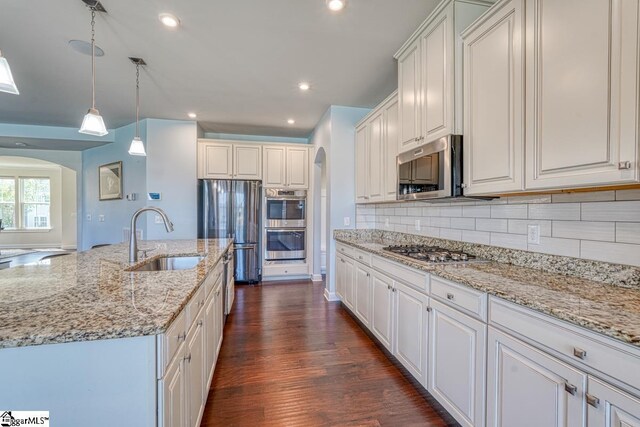 kitchen featuring stainless steel appliances, white cabinets, sink, dark hardwood / wood-style floors, and backsplash