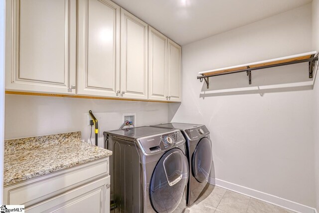 laundry room with light tile patterned flooring, separate washer and dryer, and cabinets