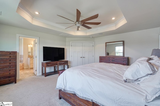 carpeted bedroom featuring a closet, connected bathroom, ceiling fan, and a raised ceiling