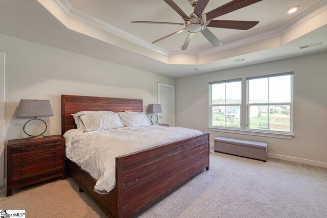 carpeted bedroom featuring ceiling fan, crown molding, and a tray ceiling