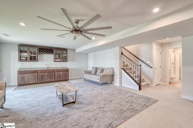 living room featuring light carpet, sink, and ceiling fan