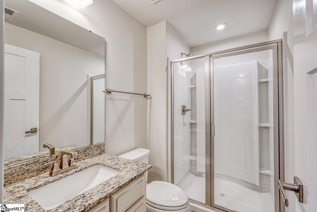 bathroom featuring a shower with door, toilet, and vanity