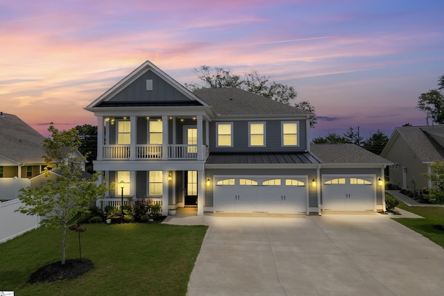 view of front facade featuring a porch, a balcony, a yard, and a garage