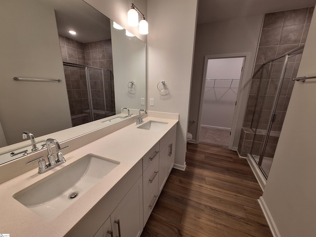 bathroom with wood-type flooring, toilet, an enclosed shower, and vanity