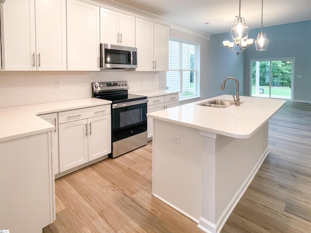 kitchen with sink, appliances with stainless steel finishes, hanging light fixtures, white cabinets, and a center island with sink