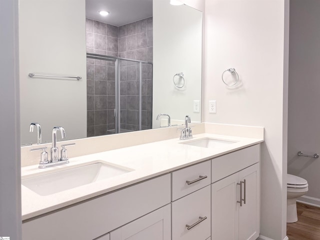 bathroom featuring vanity, hardwood / wood-style floors, a shower with door, and toilet