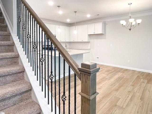 staircase featuring a notable chandelier, ornamental molding, wood finished floors, recessed lighting, and baseboards