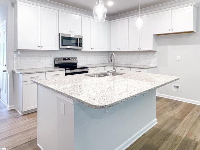 kitchen featuring decorative light fixtures, sink, light stone counters, white cabinets, and appliances with stainless steel finishes