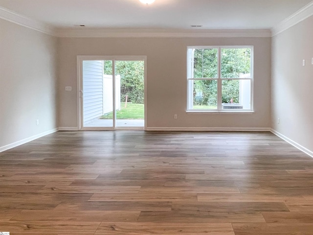 spare room with a healthy amount of sunlight, crown molding, and wood finished floors