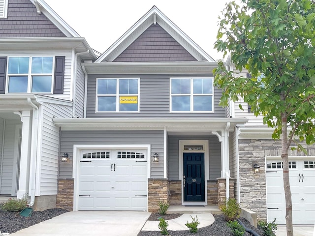 view of front of home featuring an attached garage, stone siding, and driveway