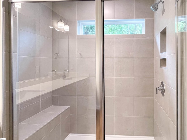 bathroom featuring a shower with shower door and plenty of natural light