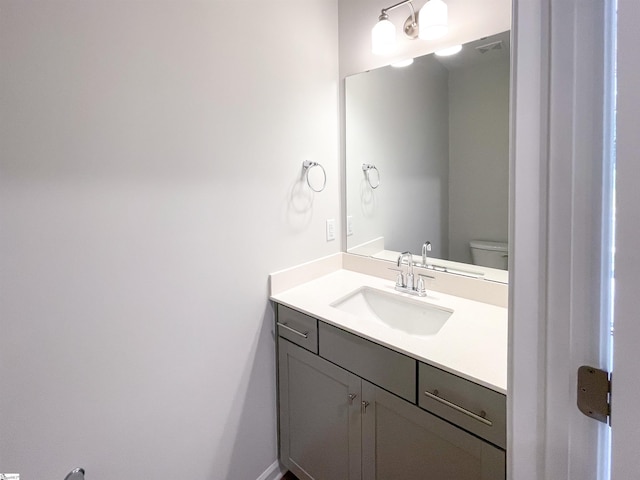 bathroom with vanity, toilet, and visible vents