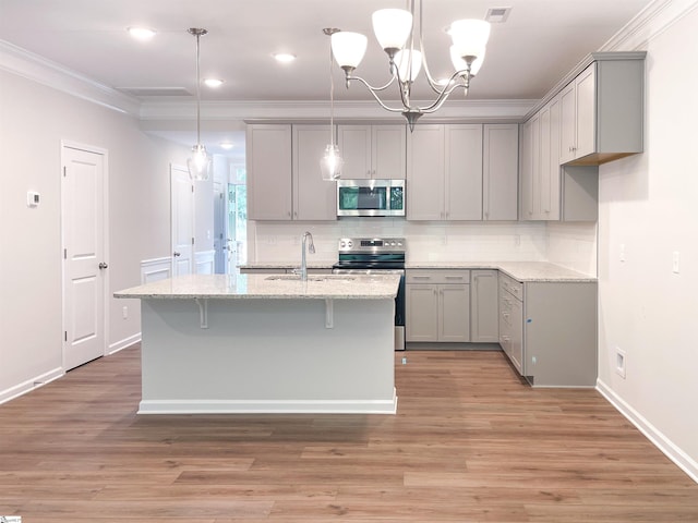 kitchen with light wood-type flooring, sink, an inviting chandelier, stainless steel appliances, and light stone countertops