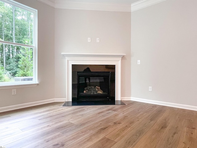 unfurnished living room with light wood-type flooring, crown molding, and a healthy amount of sunlight