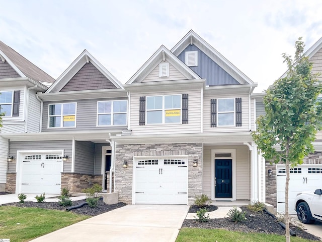 view of front of house with stone siding, an attached garage, board and batten siding, and driveway